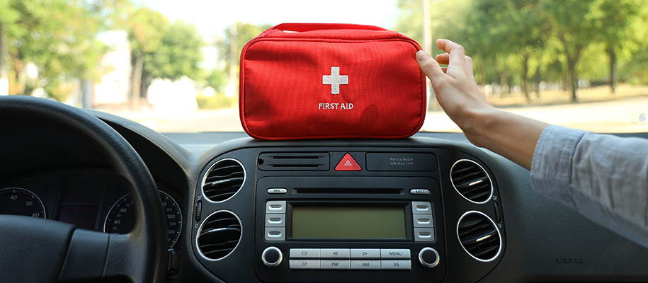 Arm of White person in car passenger seat reading for first aid kit on dashboard