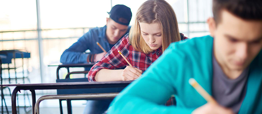 Young White woman in red plaid shirt taking test at desk between two men