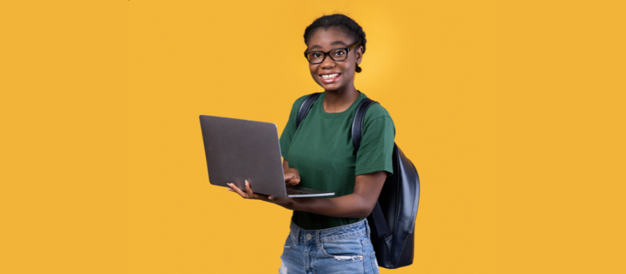 Young Black woman with glasses in green shirt, holding laptop, wearing backpac