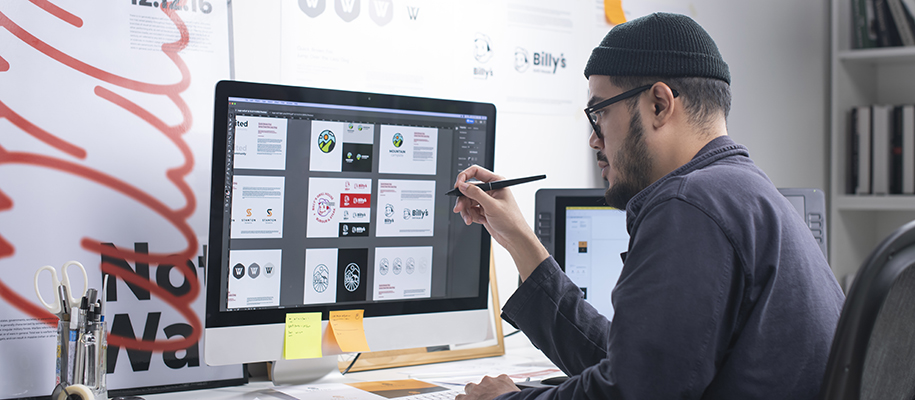 Asian man in beanie at desk working on digital marketing design projects