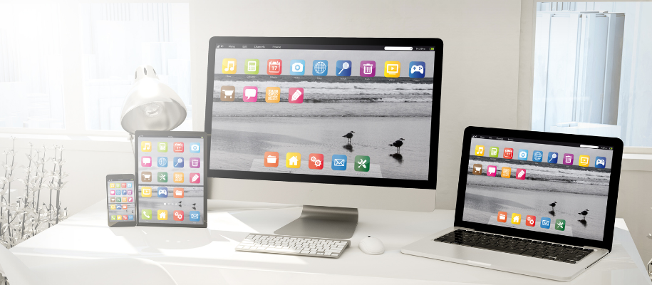 White desk with desktop computer, laptop, table, and phone with same apps