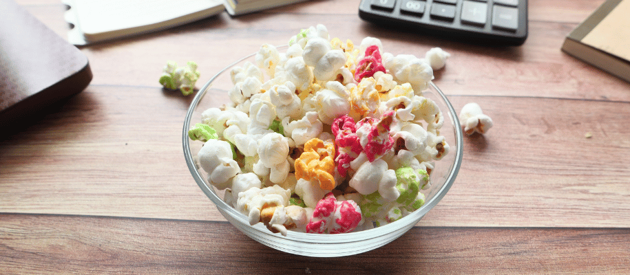 A bowl of multi-colored popcorn on a desk