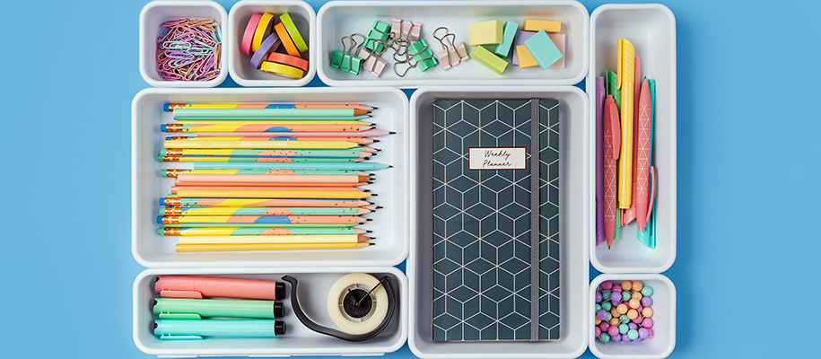 Organized white trays with pencils, planners, pins binder clips, and more
