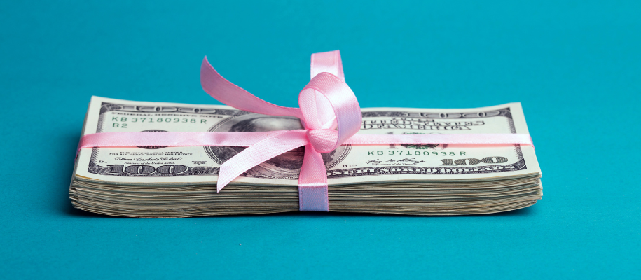 Thick stack of $100 bills wrapped in pink ribbon against blue background