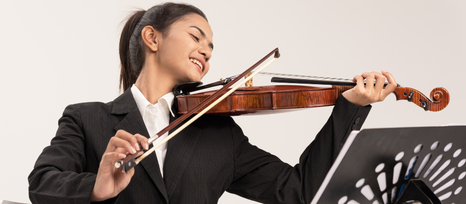 Southeast Asian woman joyfully playing violin for an audition in black blazer