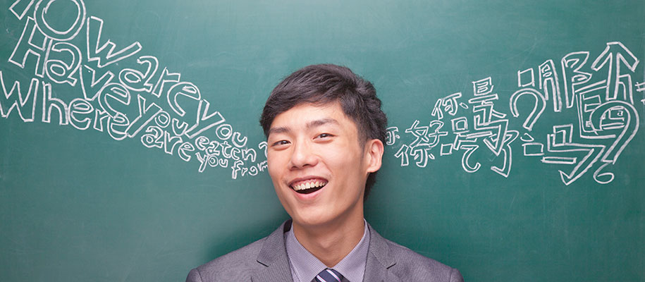 Young Asian male in front of blackboard with Chinese and English script written