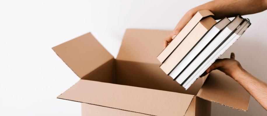 Close up of a stack of books being placed into a moving box