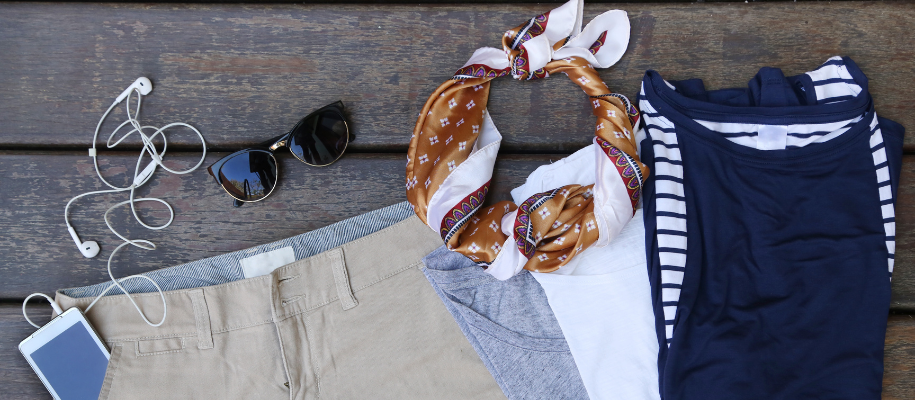 Shorts, T-shirts, ascot, sunglasses, phone laid out on picnic table