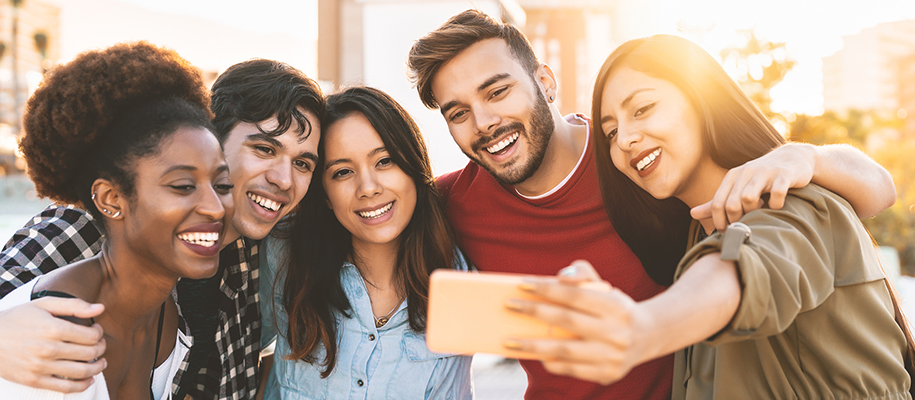 Diverse group of young people smiling while taking group photo on phone