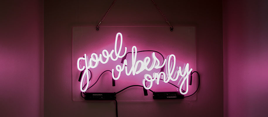 Pink neon sign hanging on wall reading good vibes only