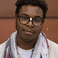 young Black man with black framed glasses and white scarf
