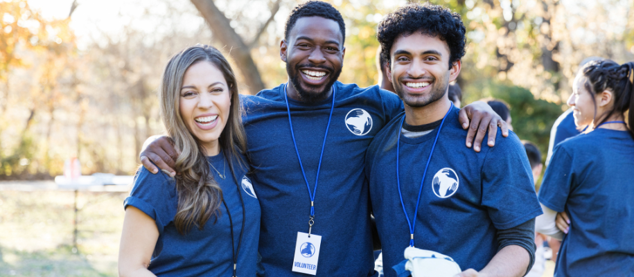 Three diverse friends volunteering outside, standing close and posing for photo