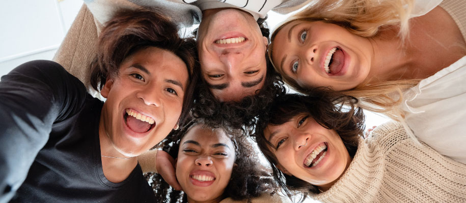 Diverse group of college friends taking selfie from below with silly faces