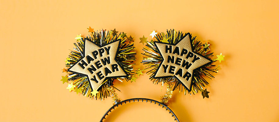 Sparkling glitter and gold Happy New Year star headband against yellow backdrop