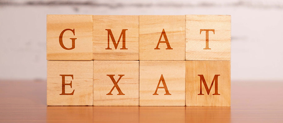 Eight wooden blocks stacked on top of each with letters reading GMAT EXAM