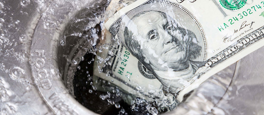 One hundred dollar bills going down the sink drain with water splashing