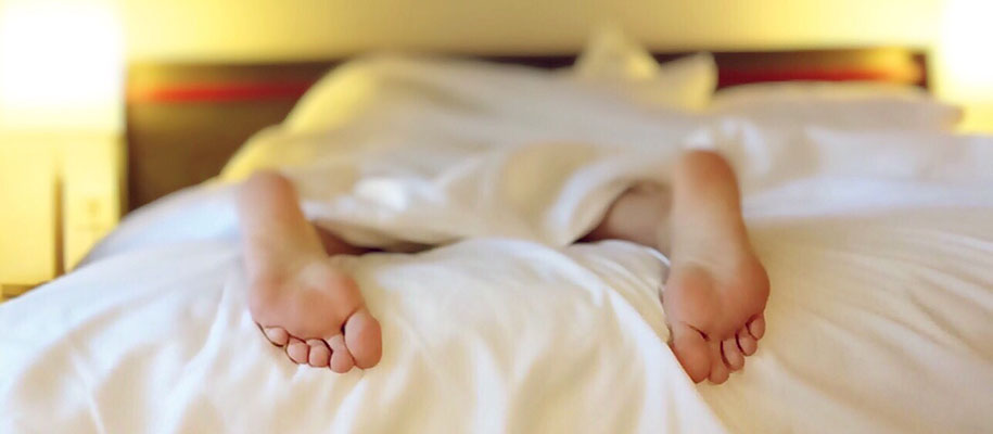 Person¿s feet sticking out at bottom of blanket with rest of bed out of focus