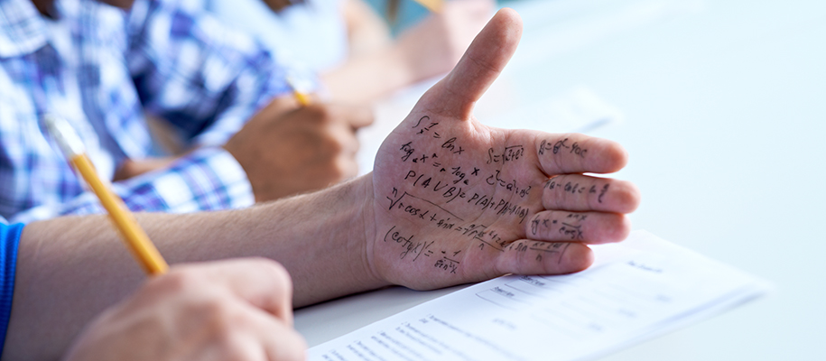 Hand of White person covered in math notes, other hand writing answers on test