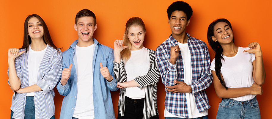 Diverse group of five students smiling and pointing thumbs at themselves
