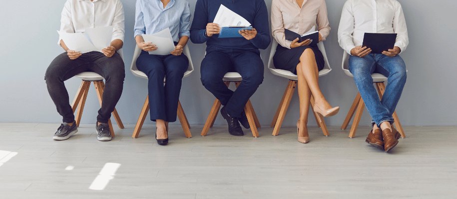 A row of men & women in chairs waiting for an interview