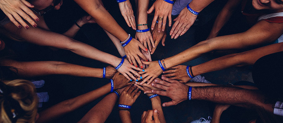 group of people stacking hands with blue bracelets on wrists