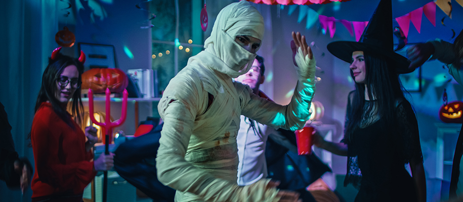 Person in mummy costume dancing at party near devil and witch