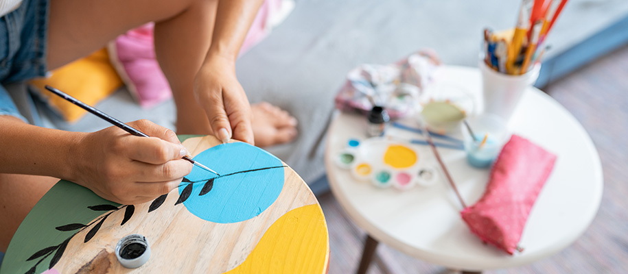 Person leaning over wooden circle painting shapes and patterns