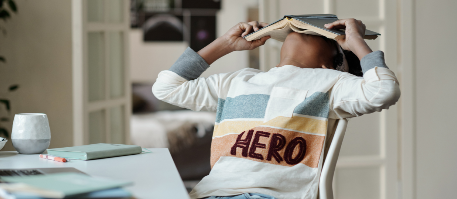 Student with book on face, procrastinating