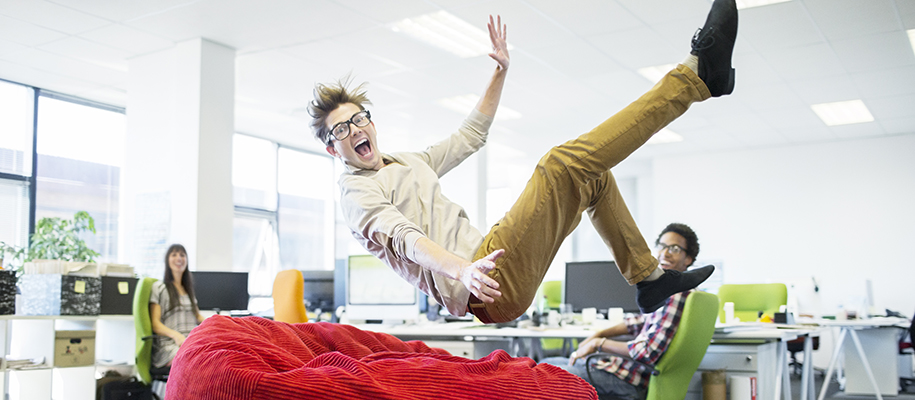 White person in business casual clothes falling back into bean bag in office