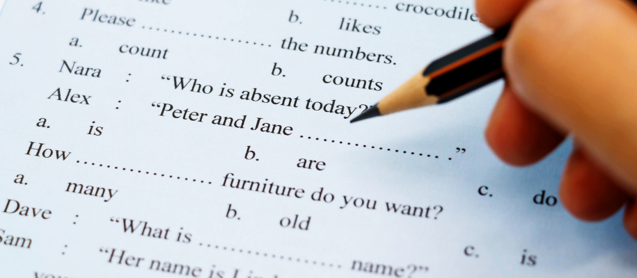 English grammar test with fingers holding pencil held over the page