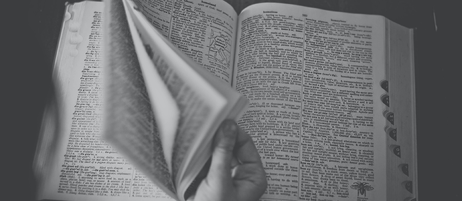 Black and white image of hand flipping through dictionary pages