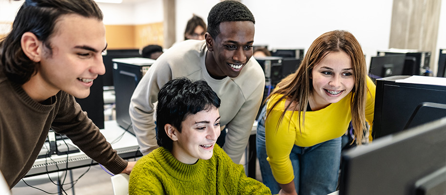 Group of diverse students smiling and working together in computer lab