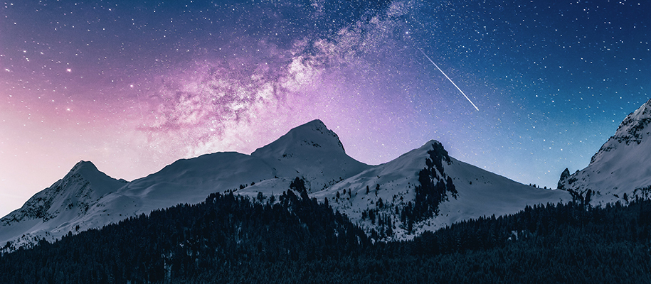 Snowcapped mountains under purple and blue night sky with shooting star