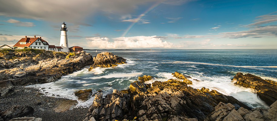 Portland Head Light in Maine, rocks, waves on semi-cloudy day with rainbow