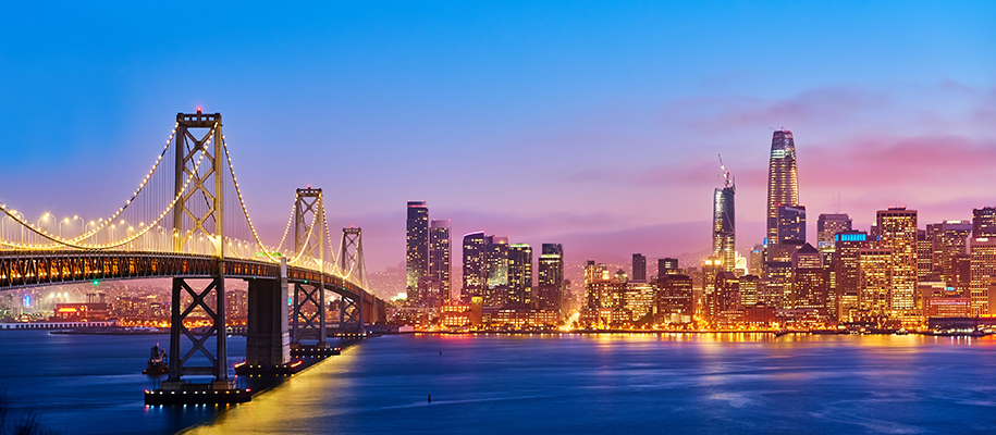 San Francisco skyline at dusk with bright orange lights and pink and blue sky