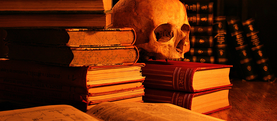 Table top with stacks of old book and skull on top of stack