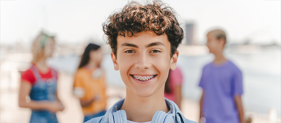 White teen boy smiling in front of group of four friends blurred behind him