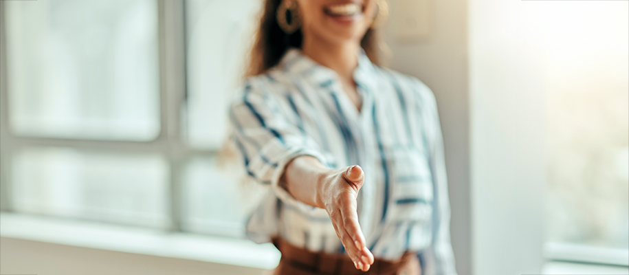 Focus on hand held out for a shake of Black woman in business attire