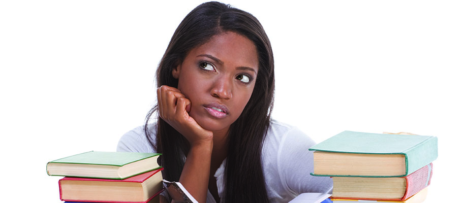 Woman in front of white background surrounded by books with head in hand