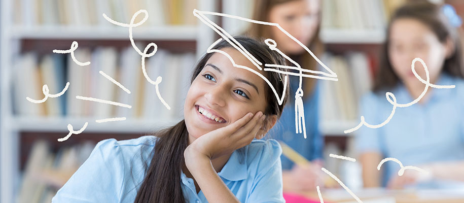 Young female student thinking and smiling in class wearing drawn graduation cap
