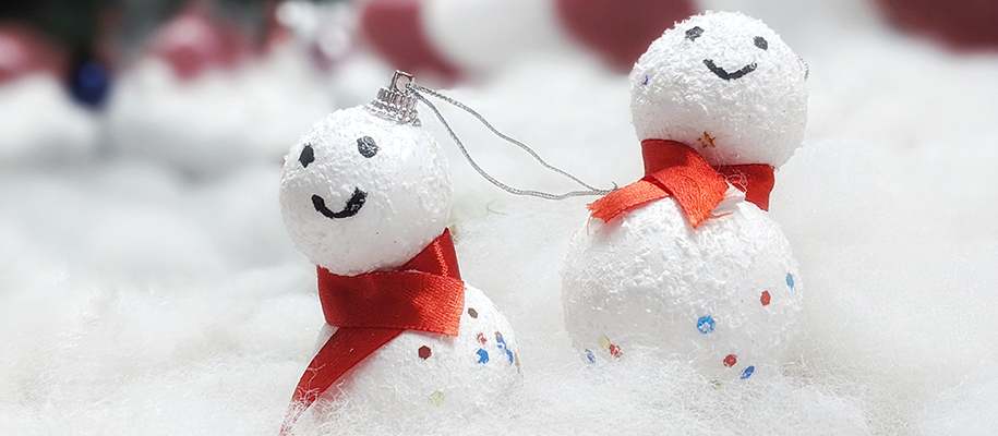 Two little snowmen decorations with smiling faces in fake snow 