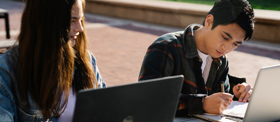 Blond White male with glasses and blue shirt looking at MacBook computer