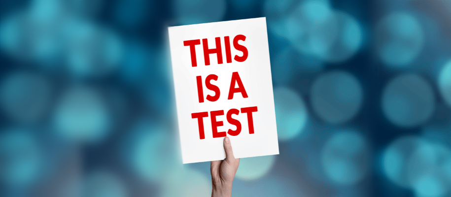 A hand holds up a sign that reads, "This is a test."