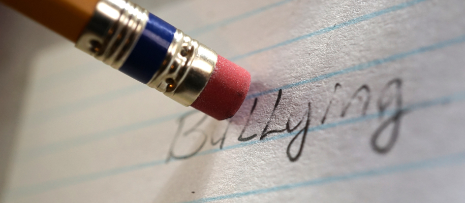 Close up of pencil eraser erasing the word bullying off line notebook paper
