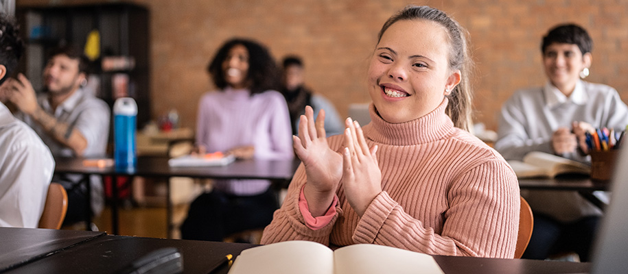 Woman with down syndrome in pink sweater clapping in college class