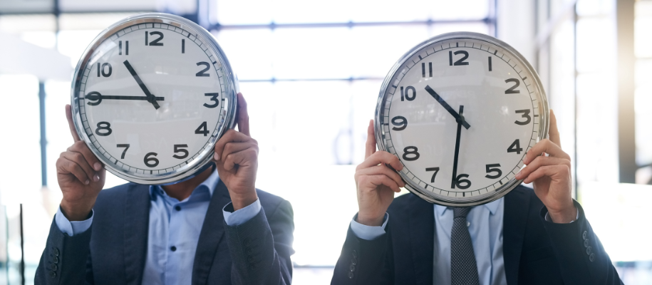 Two men in business suits holding wall clocks in front of faces