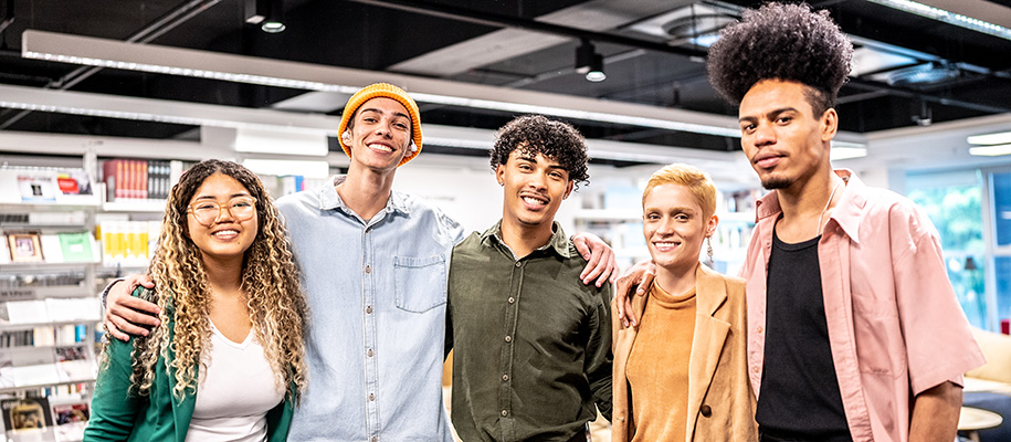 Five mixed-race college students with arms around each other at event