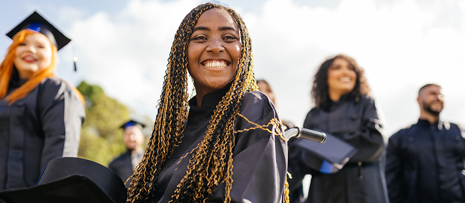 Black woman with big smile, black and yellow hair, in a wheelchair at graduation