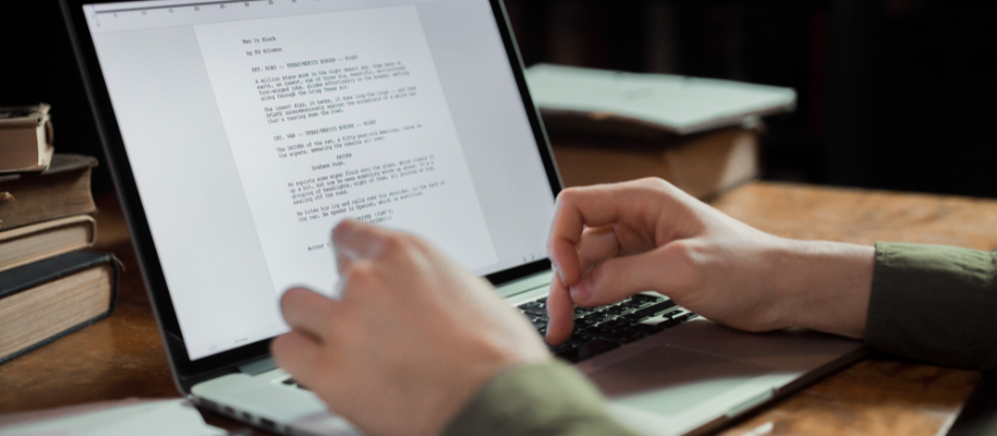Hands of White man typing script in document on lap top on wooden desk