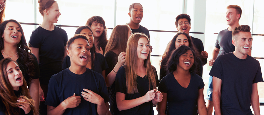 Diverse group of students in black T-shirts singing in windowed room